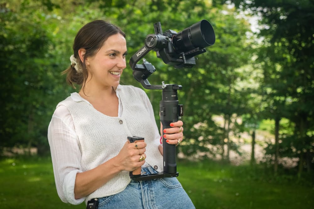A filmmaker holding a small camera on a gimbal outdoors
