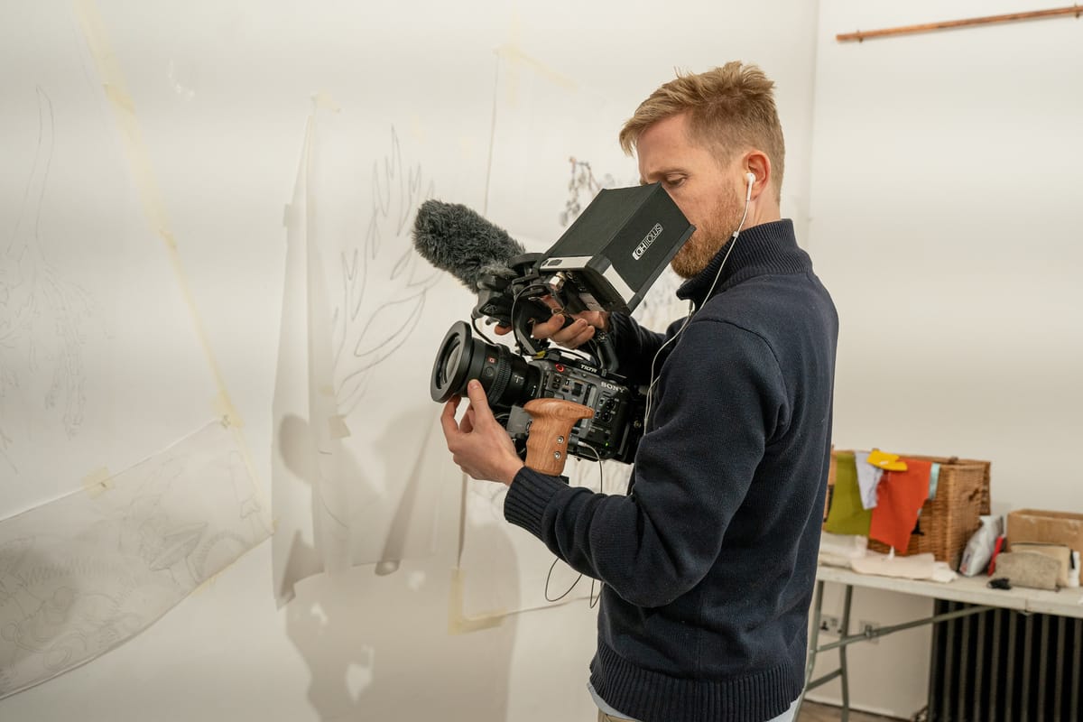Documentary filmmaker adjusting camera settings on set