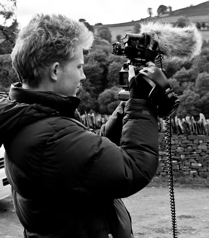 A young Sebastian filming behind the scenes with a camera and microphone