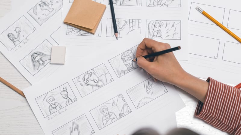 A hand sketching a storyboard on paper
