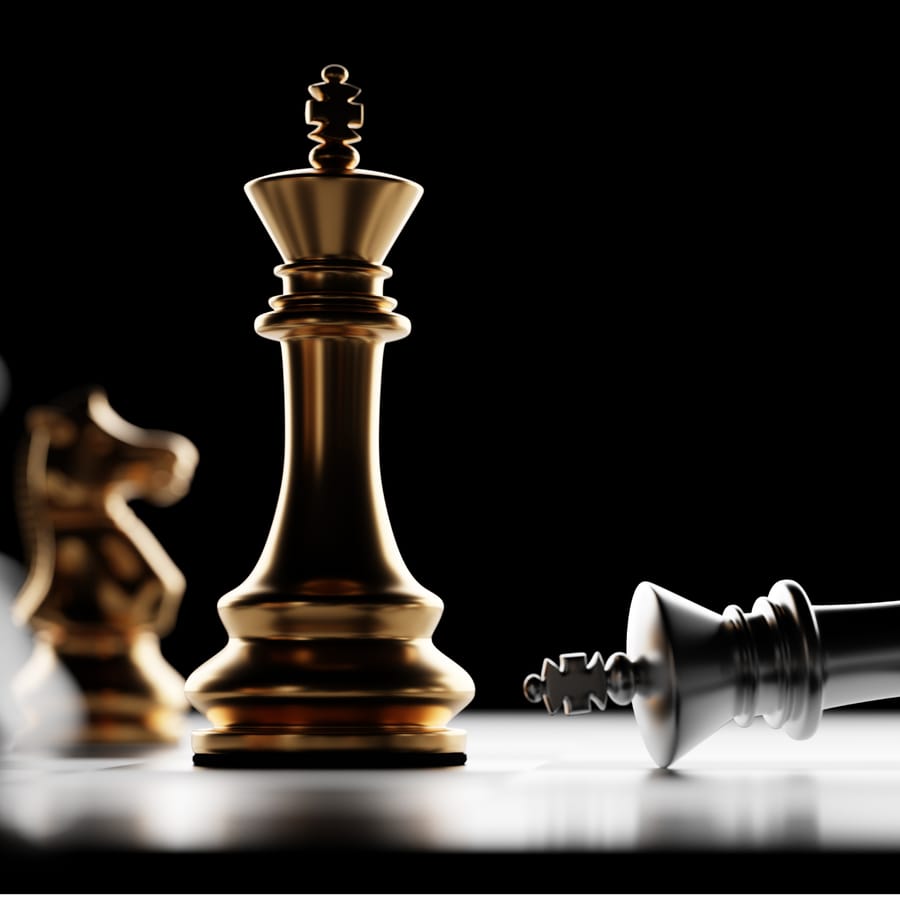 A gold chess king standing while a silver king lies fallen