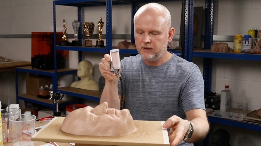 David Malinowski spattering paint onto a silicone face in his workshop