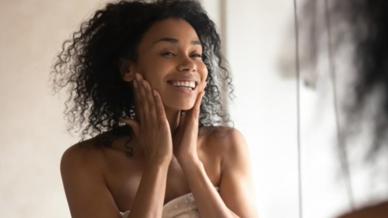 Black woman looking at herself happily in the mirror