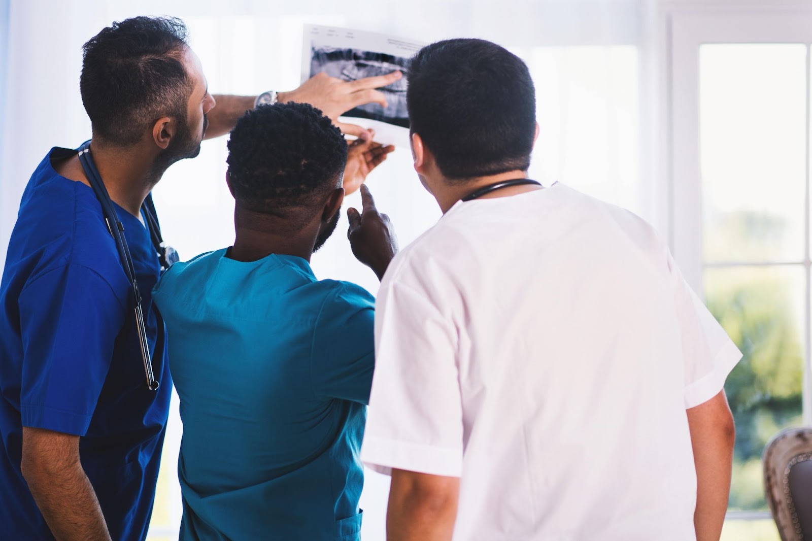 Three medical professionals look at imaging.