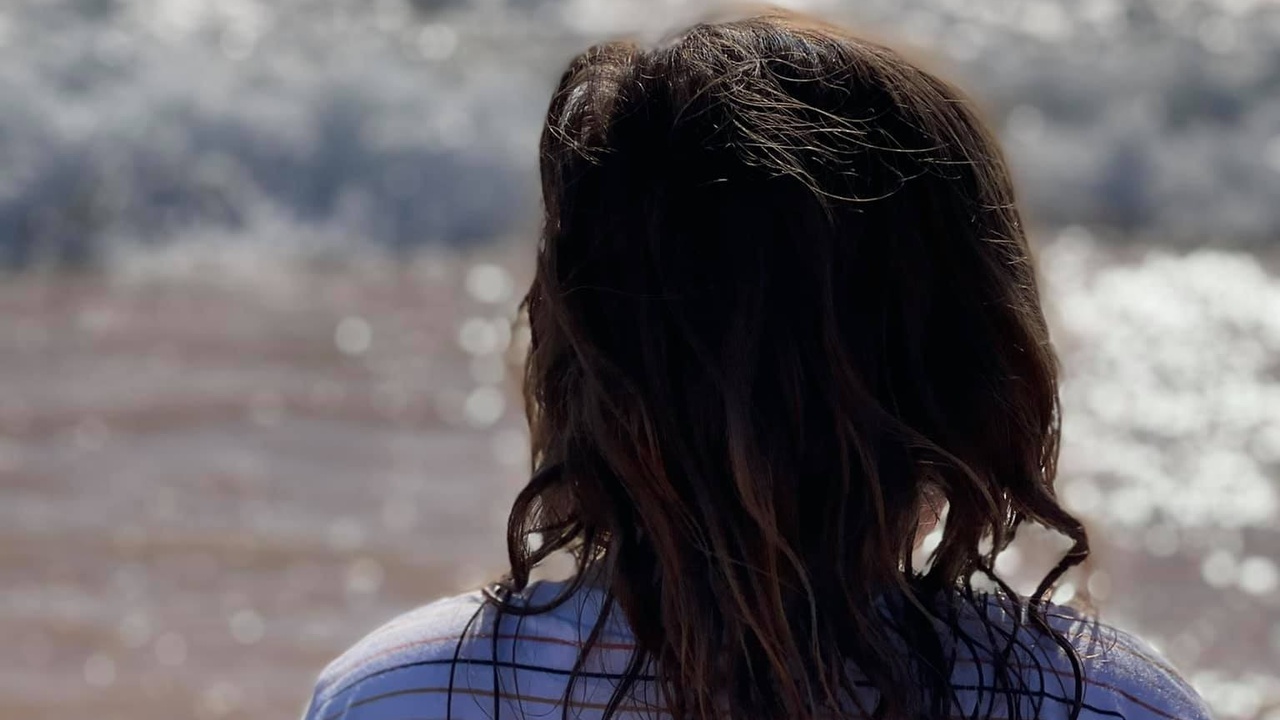 Image of a young person, with their back turned, at the beach.