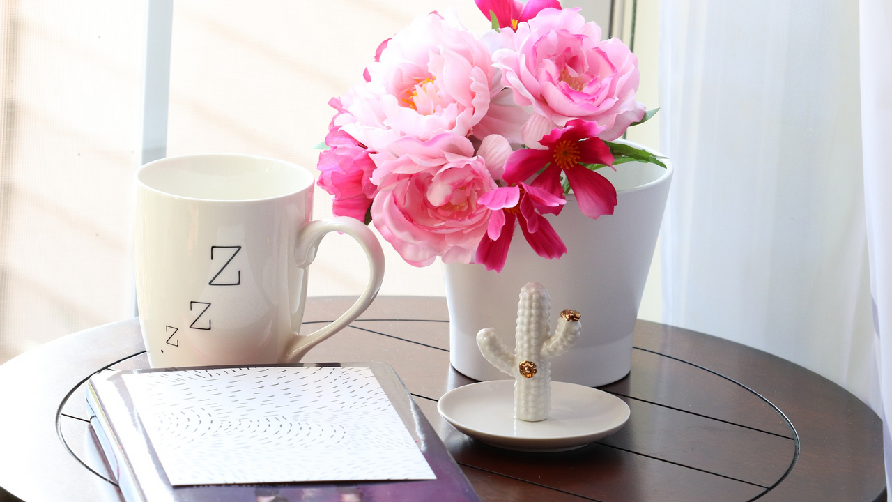 coffee table holding notebook, flowers and coffee mug