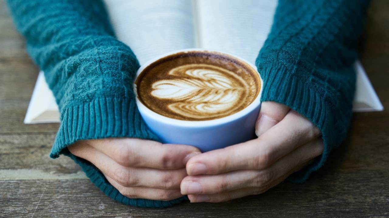 womans hands hugging a cup of coffee for comfort