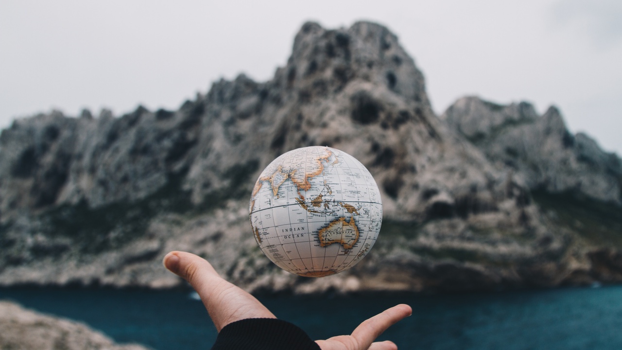 Hand catching a globe above a lake