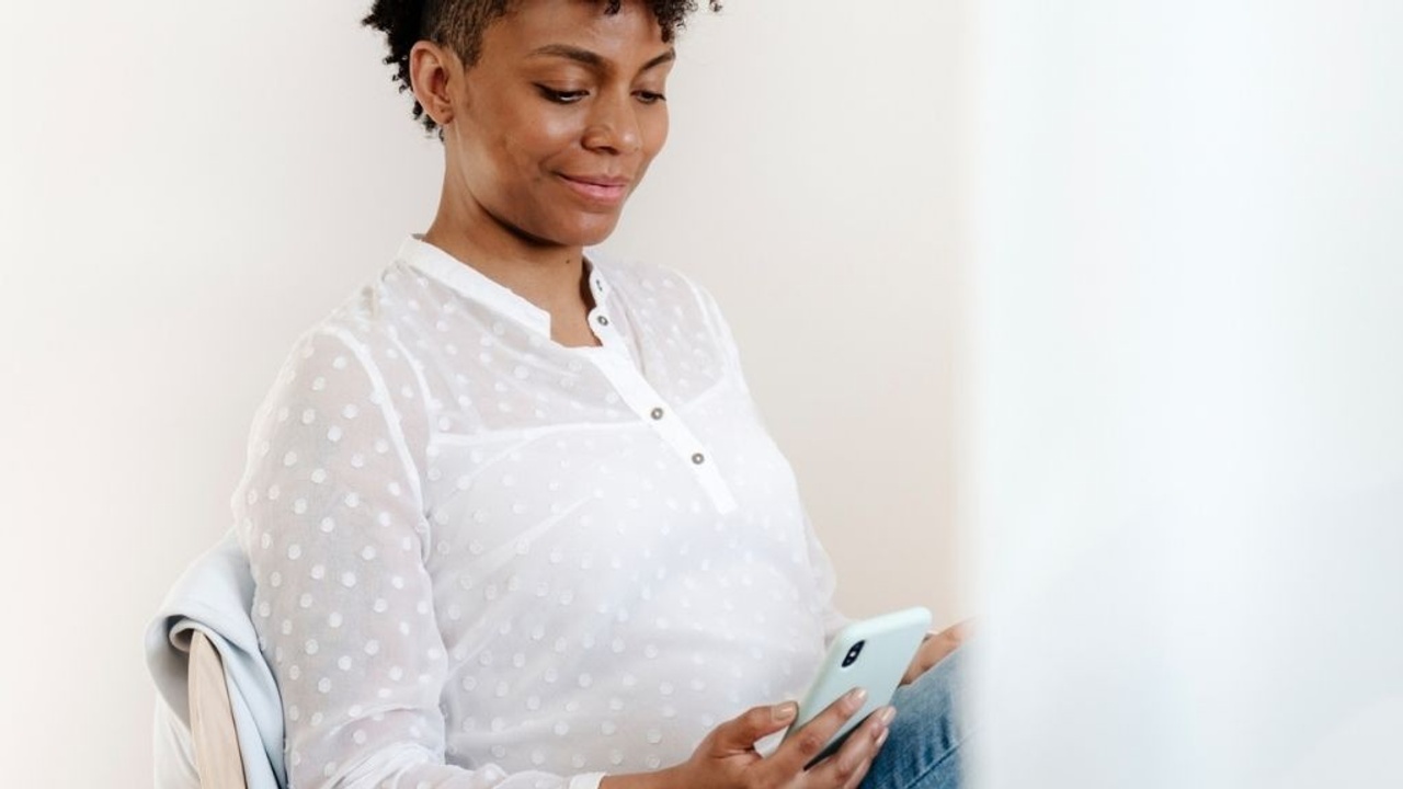 woman smiling at cell phone while seated at desk