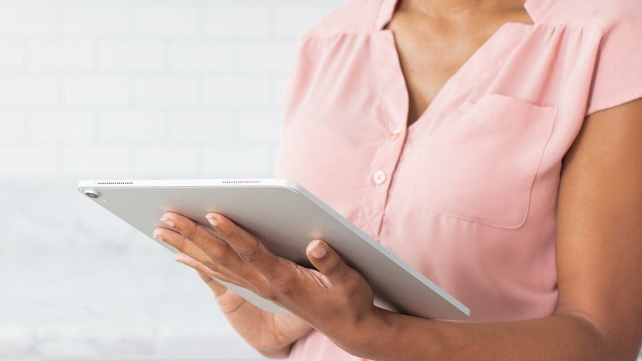 woman in pink blouse holding an ipad pro