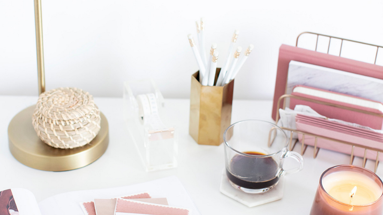 doing business internationally with ryan margolin image showing desk with coffee, candle, pink filing folders, and a gold pencil cup