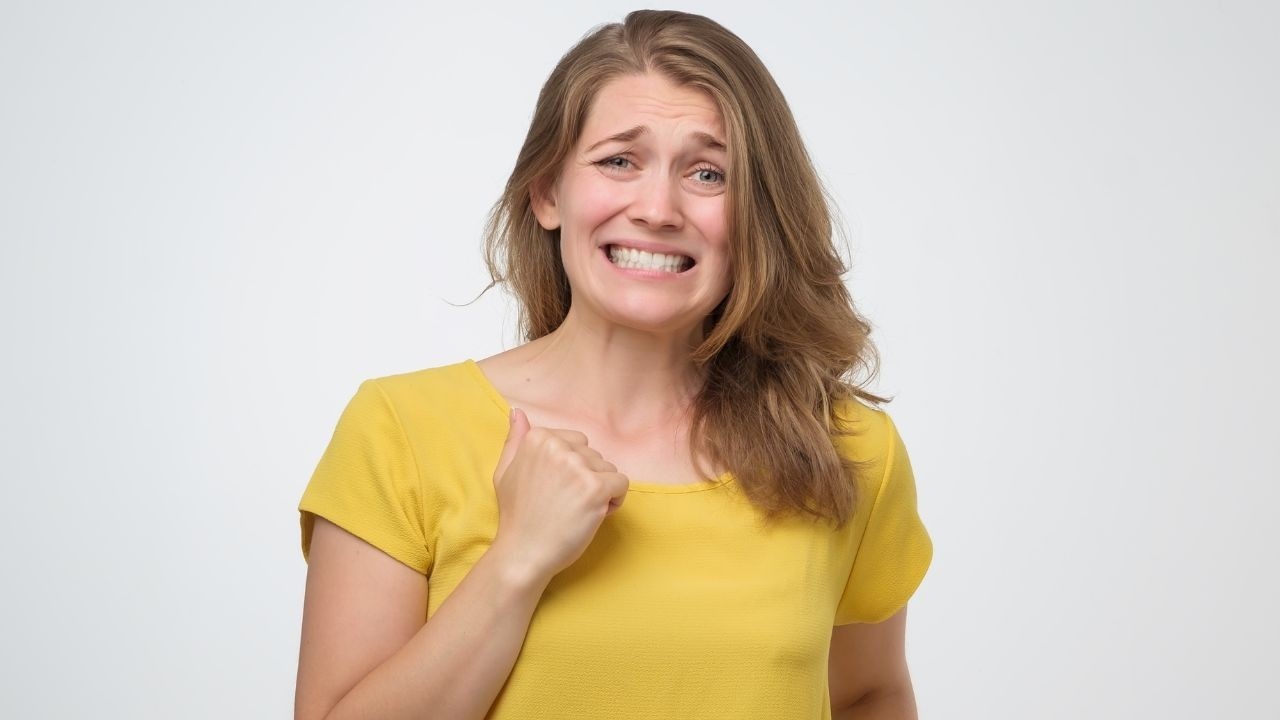 Women with a yellow shirt and a guilty look on her face. 