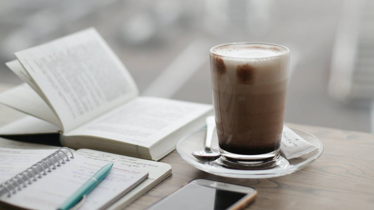 Coffee, cafe, latte, cappuccino, foam, clear glass cup, journal, pen, phone, book, morning routine.