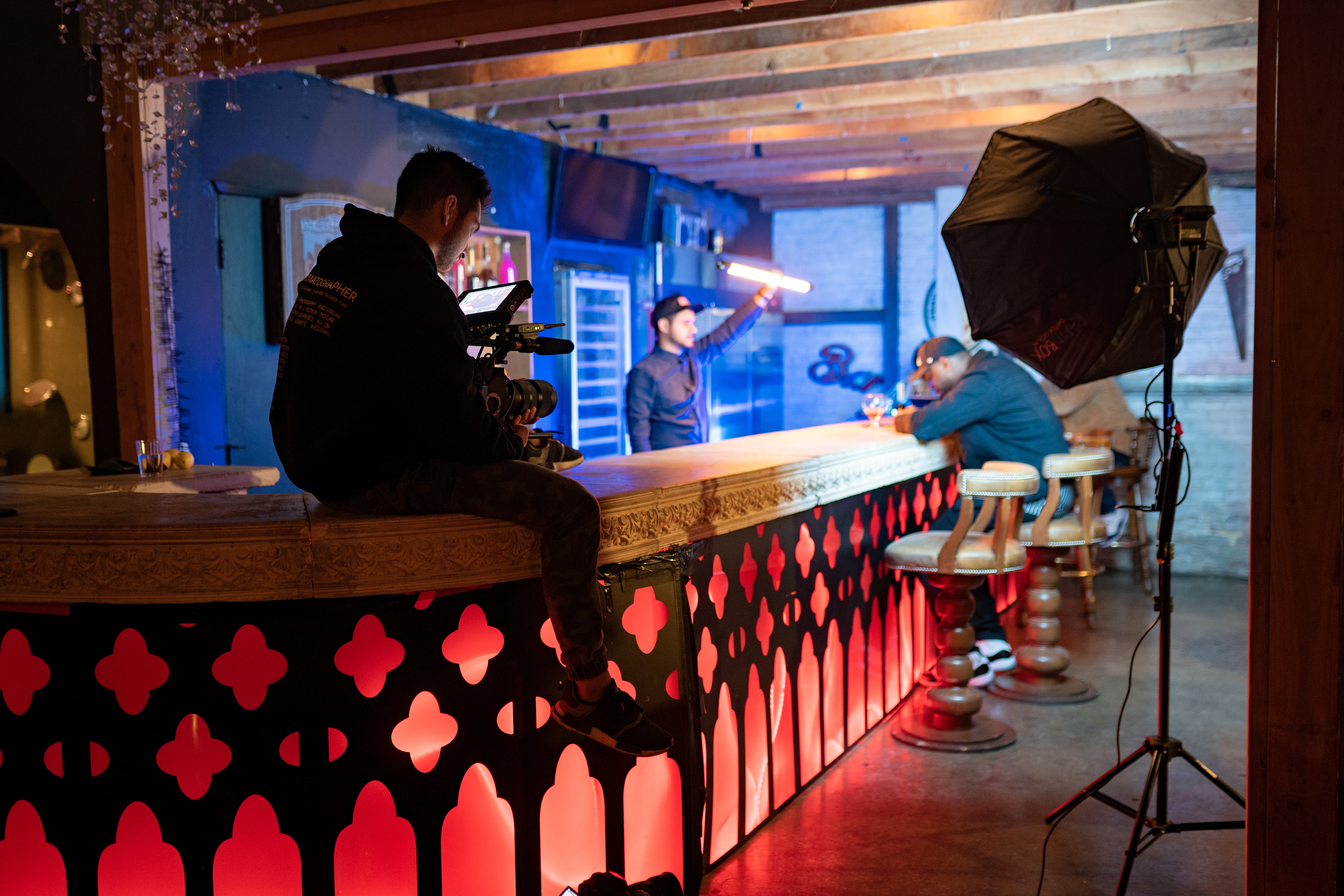 Cameraman filming a two men sitting at a bar.