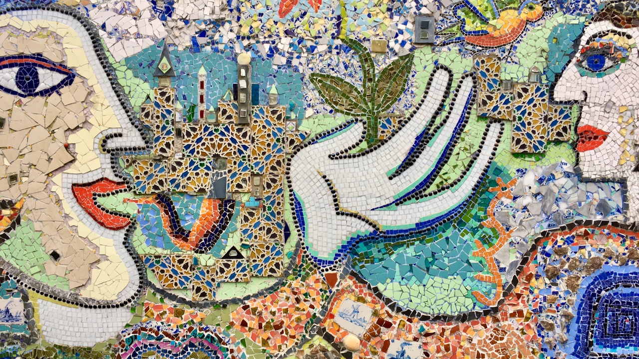 tile mosaic of two heads facing each other talking, white hand in between