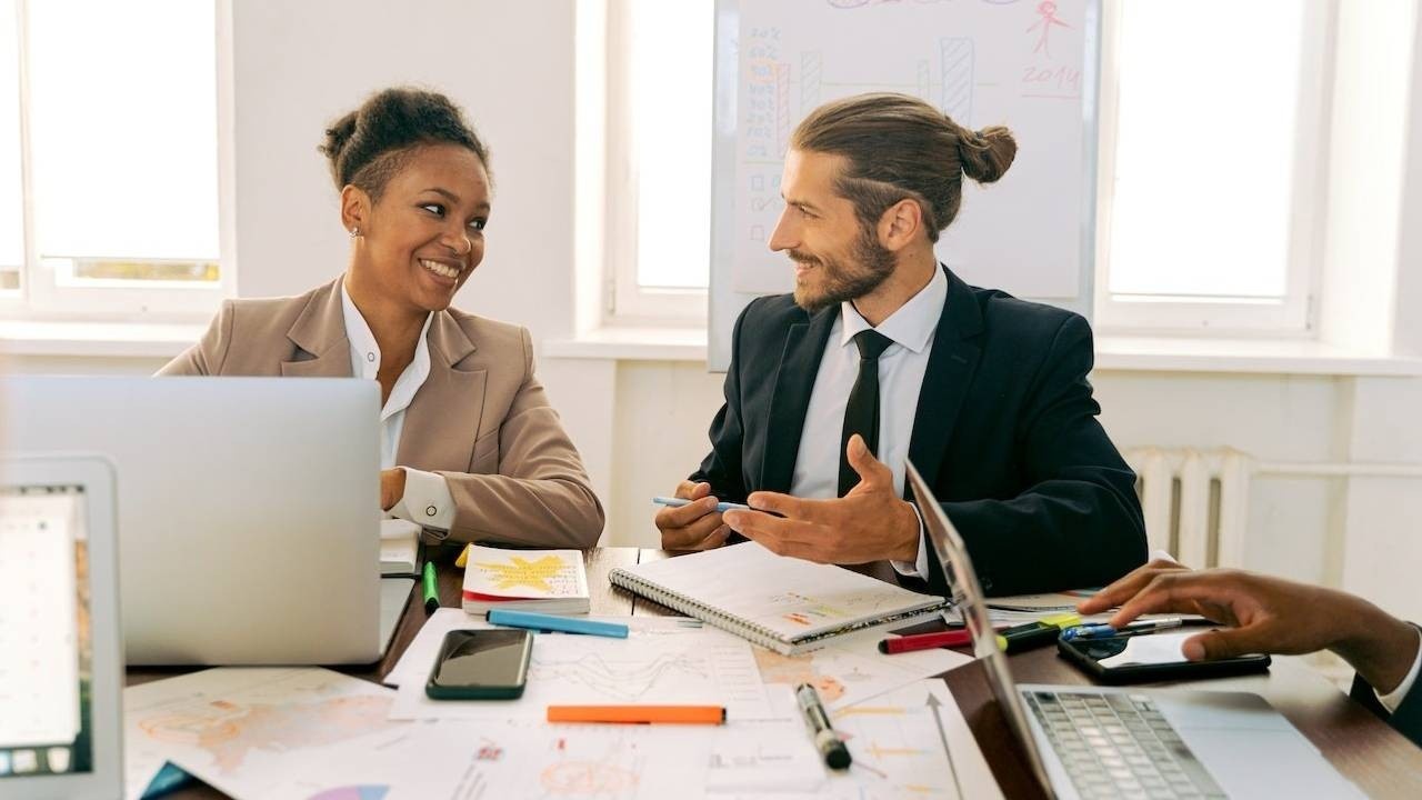 Two employees smiling and talking at work