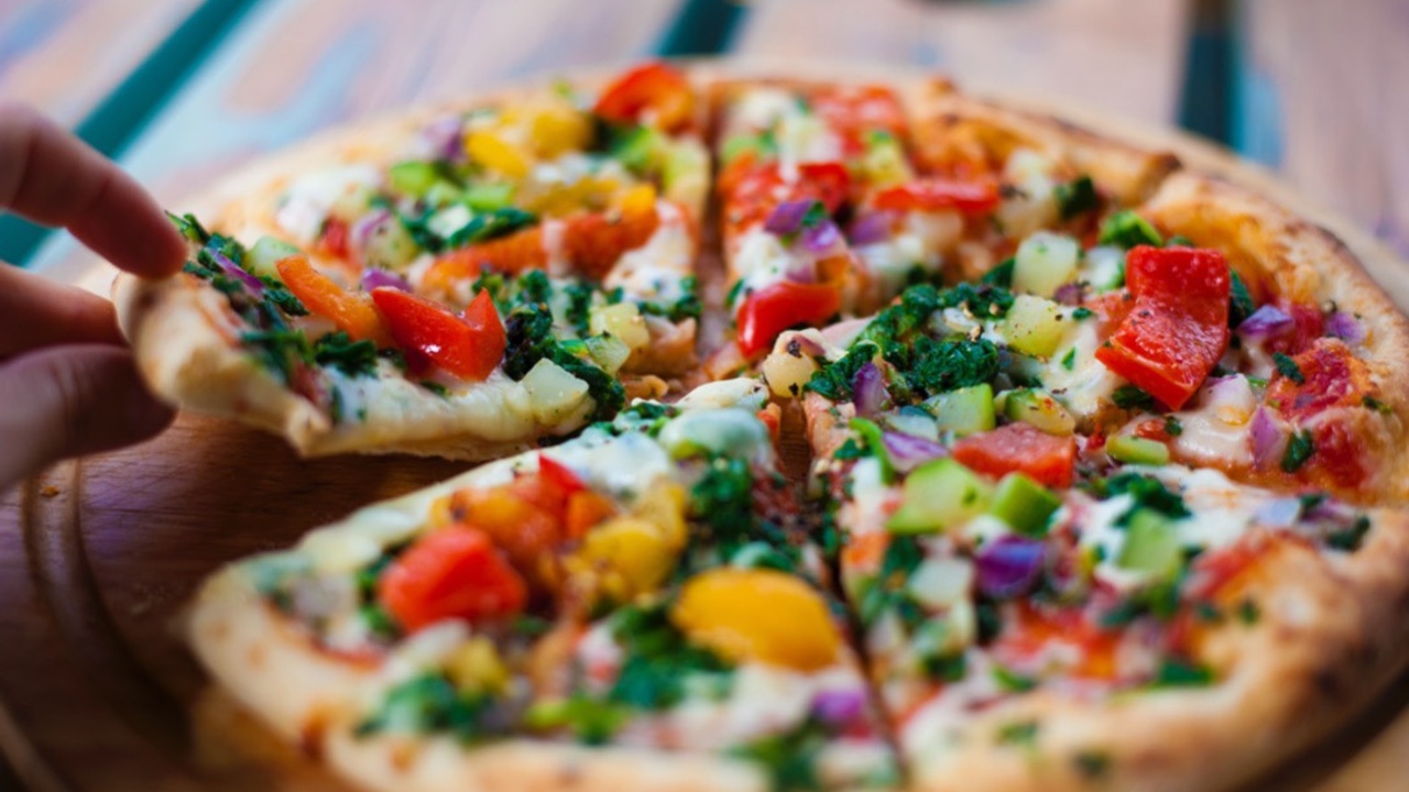 vegetarian sliced pizza with onion, bell pepper, zucchini and basil