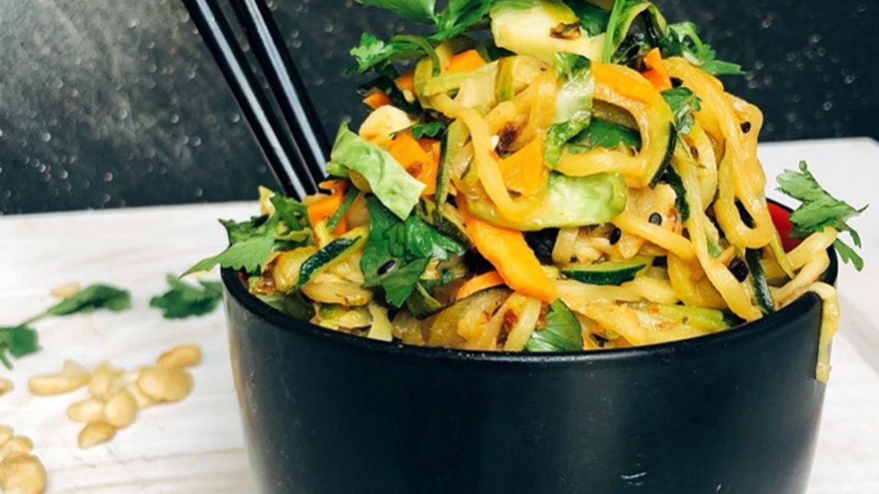 bowl of asian zoodles and sweet potato noodles with cilantro on top chop sticks in the bowl