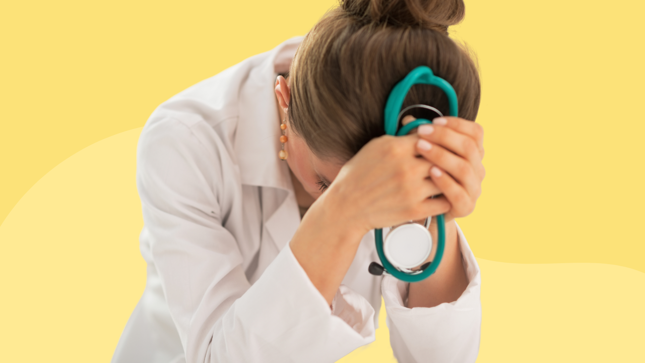 A healthcare professional in distress, leaning forward with her head resting on her hand, holding a stethoscope, on a yellow background.