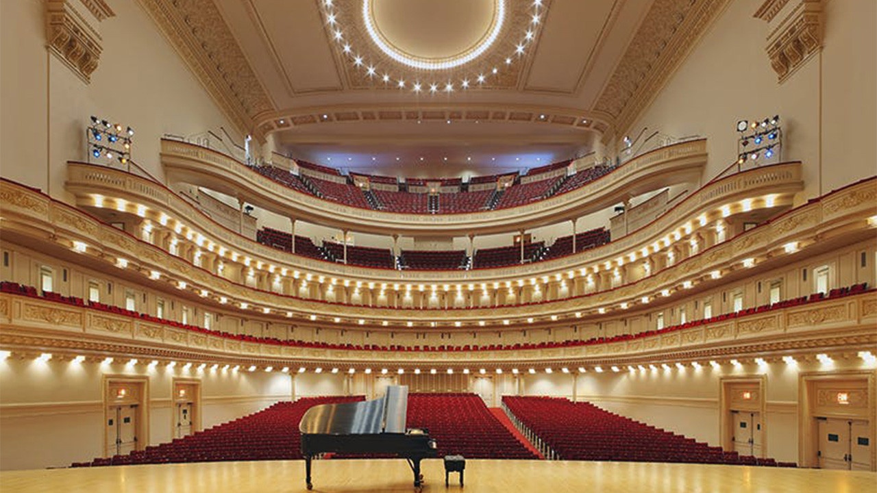 piano on stage with empty audience seats