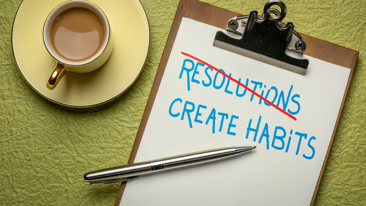 Coffee and Paper pad with the words Resolution crossed out and 'Create Habits' written in it's place