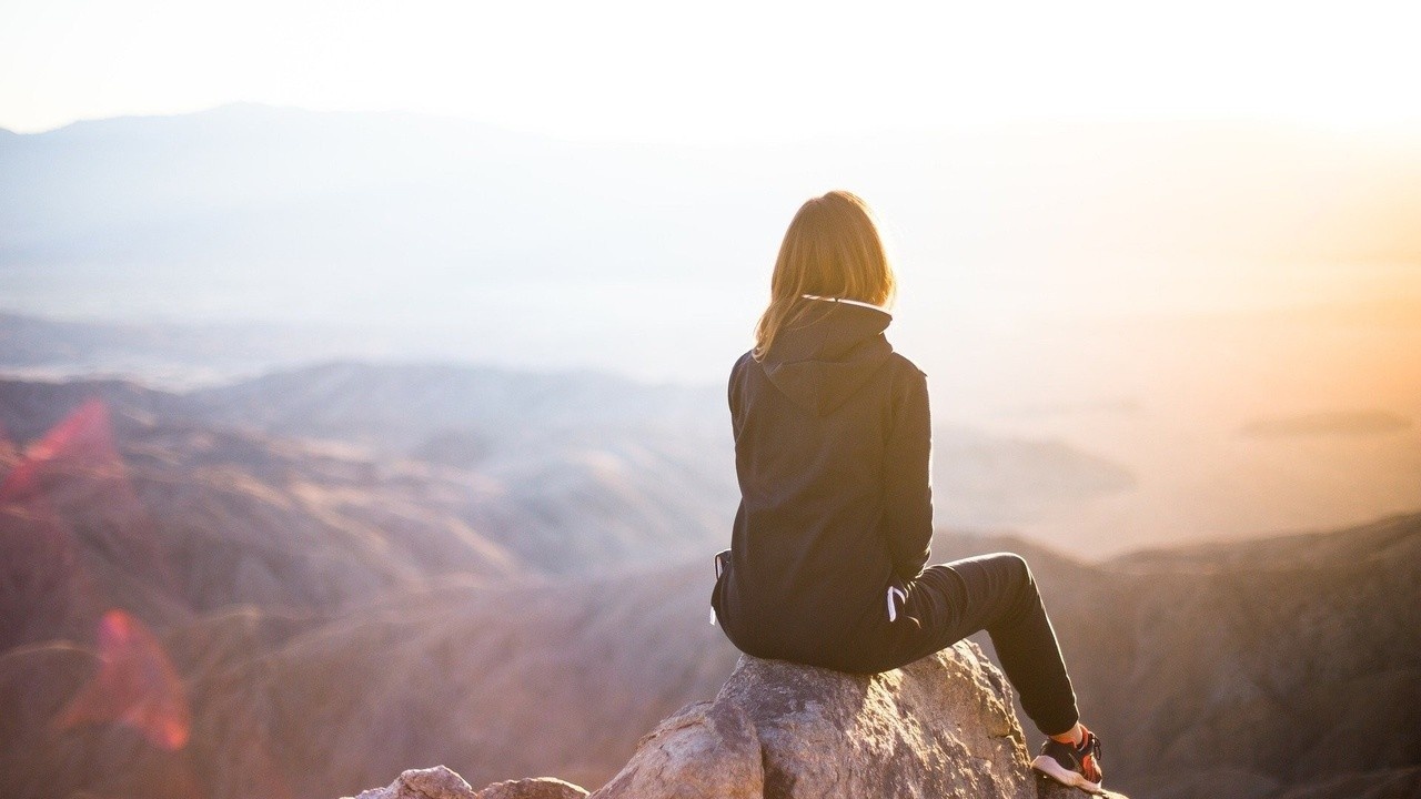 A Woman sits on a mountain top by StockSnap of Pixabay