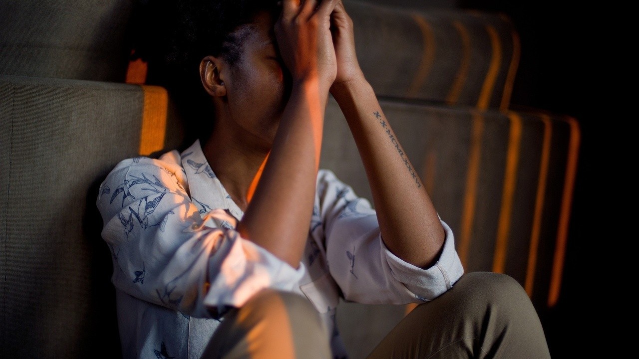 Woman sits holding her head in her hands against a sofa by 1388843 of Pixabay