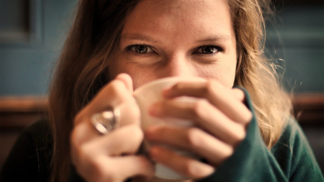 A  smiling woman holding a white mug