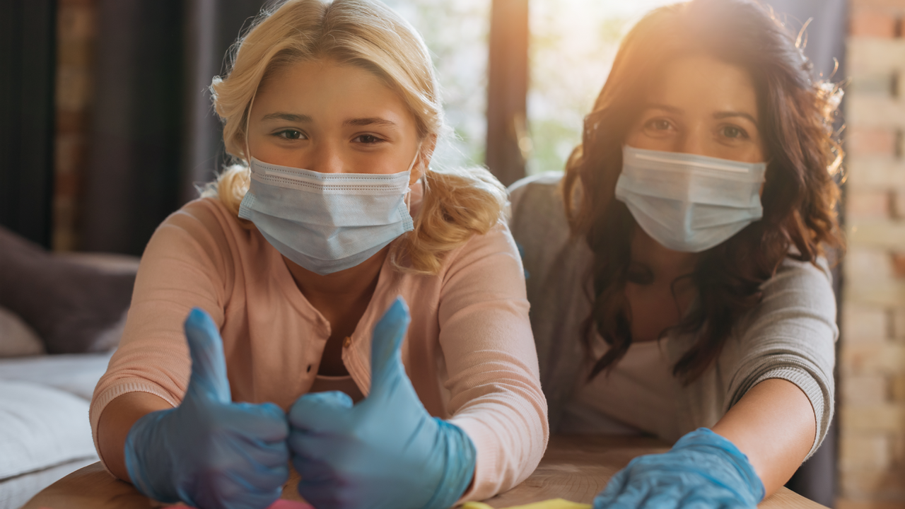 Two women giving thumbs up wearing masks