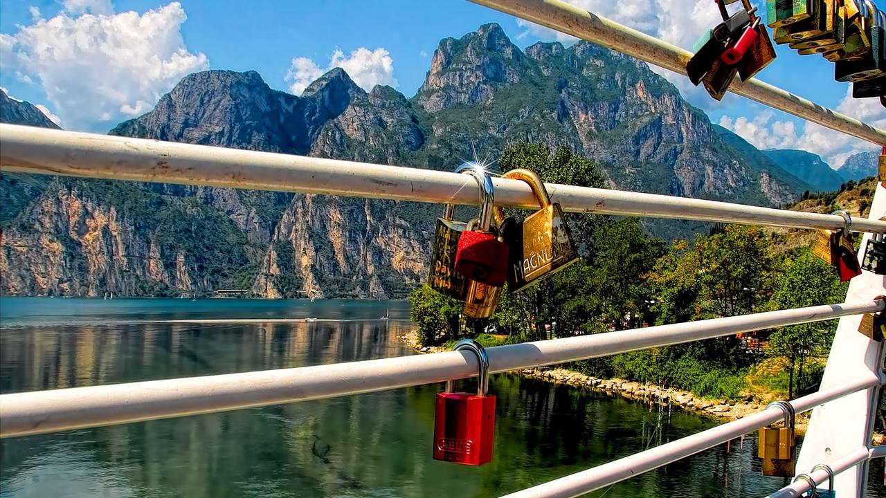 Locks on a bridge overlooking a lake with a mountain in the background.