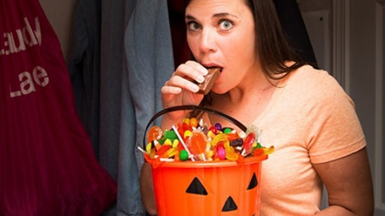 A woman hiding in a closet sneaks her kids Halloween candy