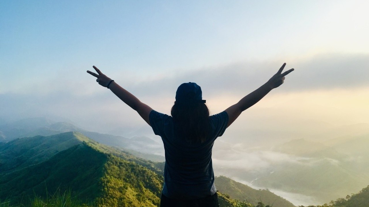 confident woman at the top of a mountain