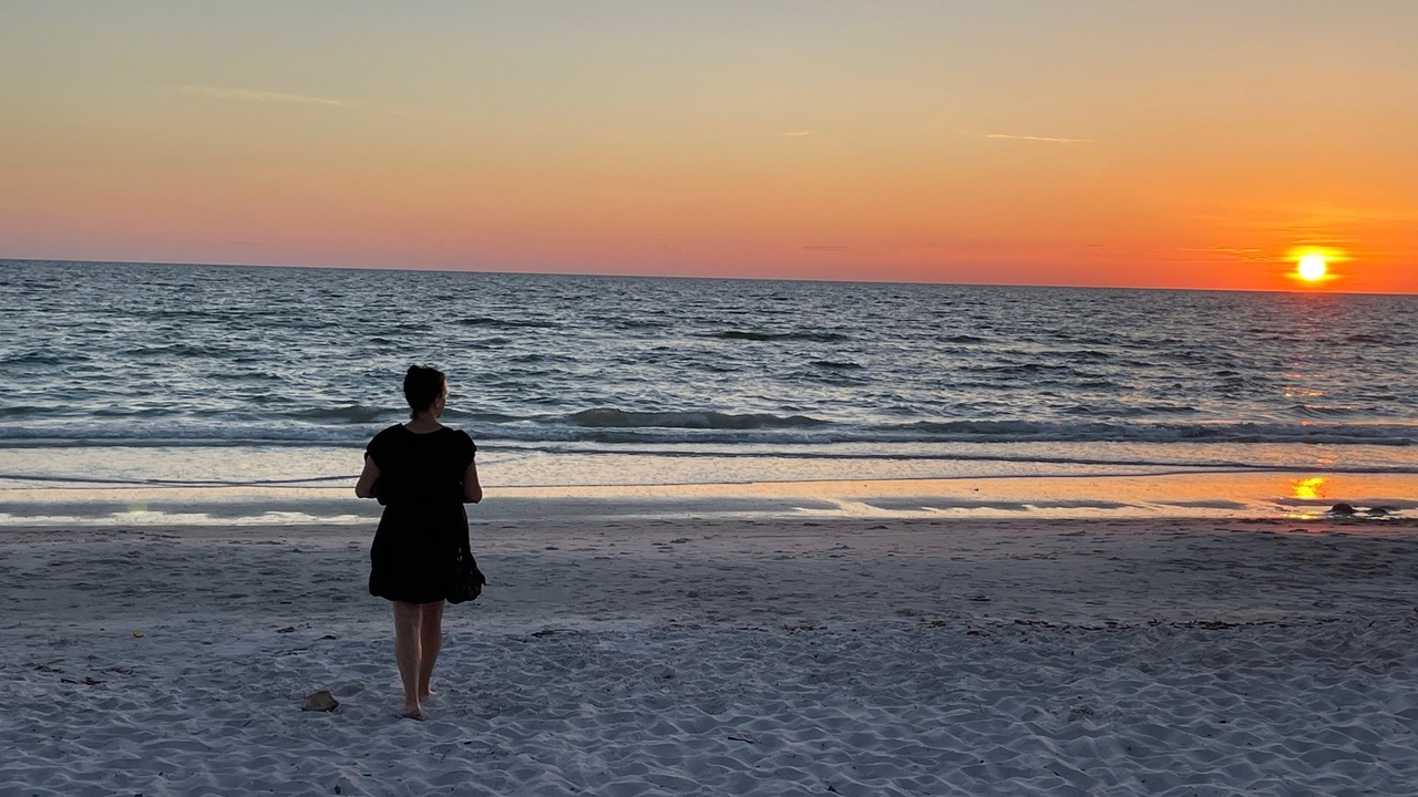 Karey standing on a beach at sunset