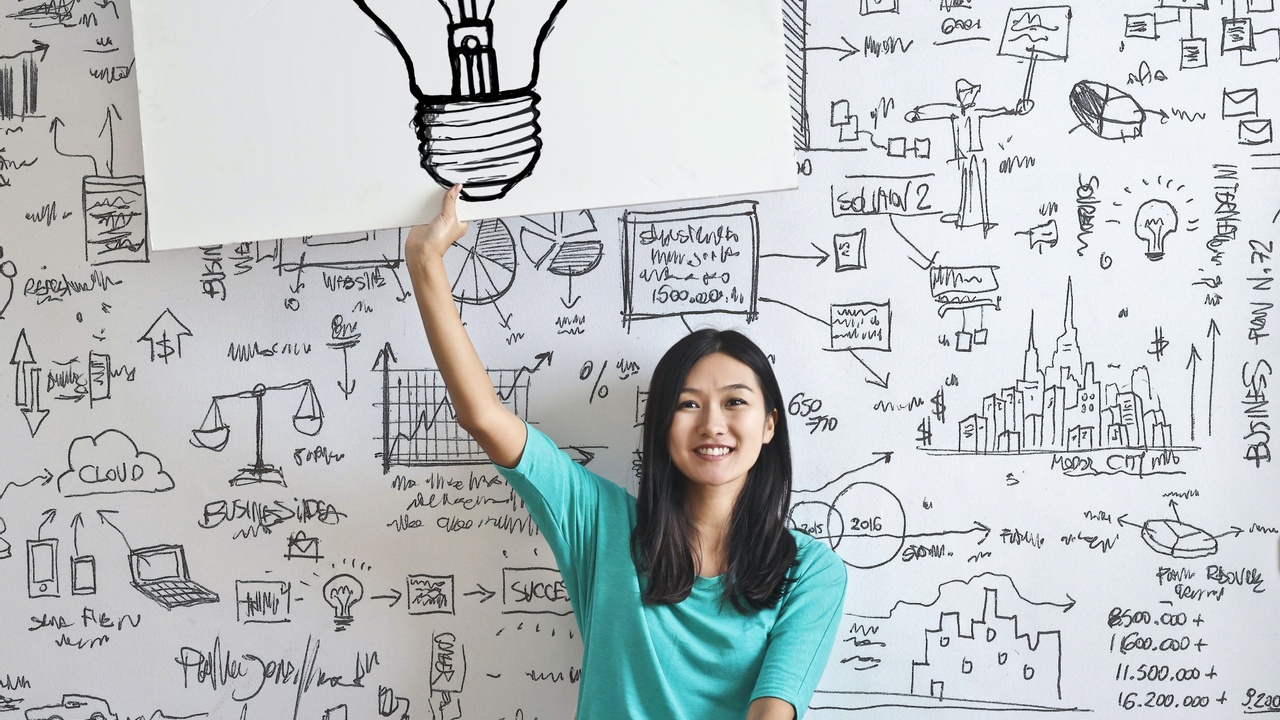 Woman holding picture of lightbulb with designs on wall