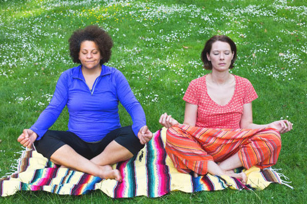 two women meditating as part of their holistic healing