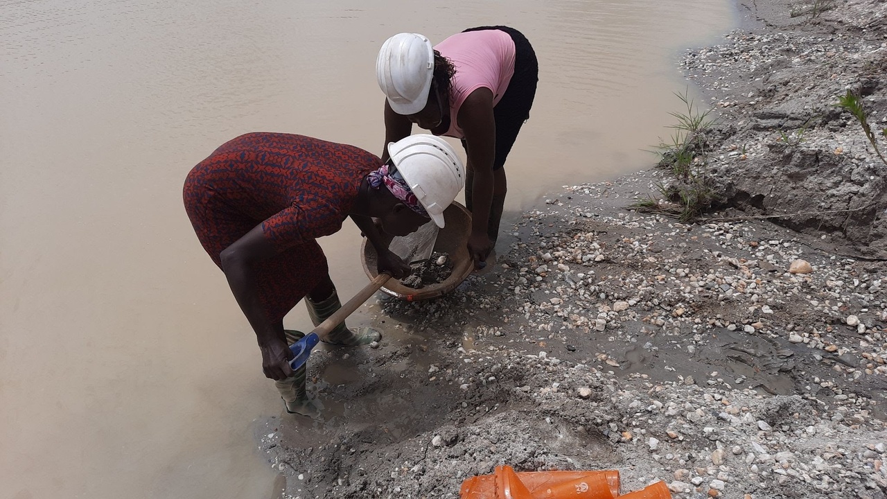 two gold miners working on a river bank