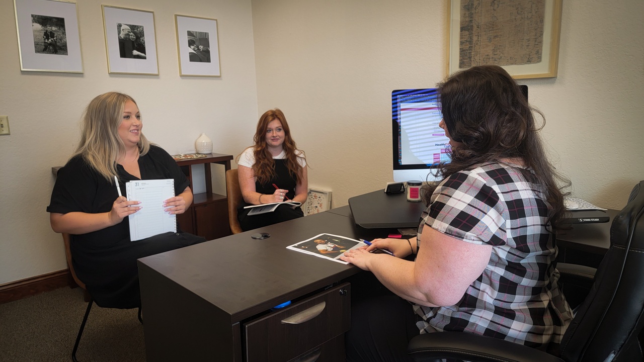 Healthcare Express's Chief Branding Officer, Lauren Butler, having a meeting with two of her team members, Lexie and Brooke.