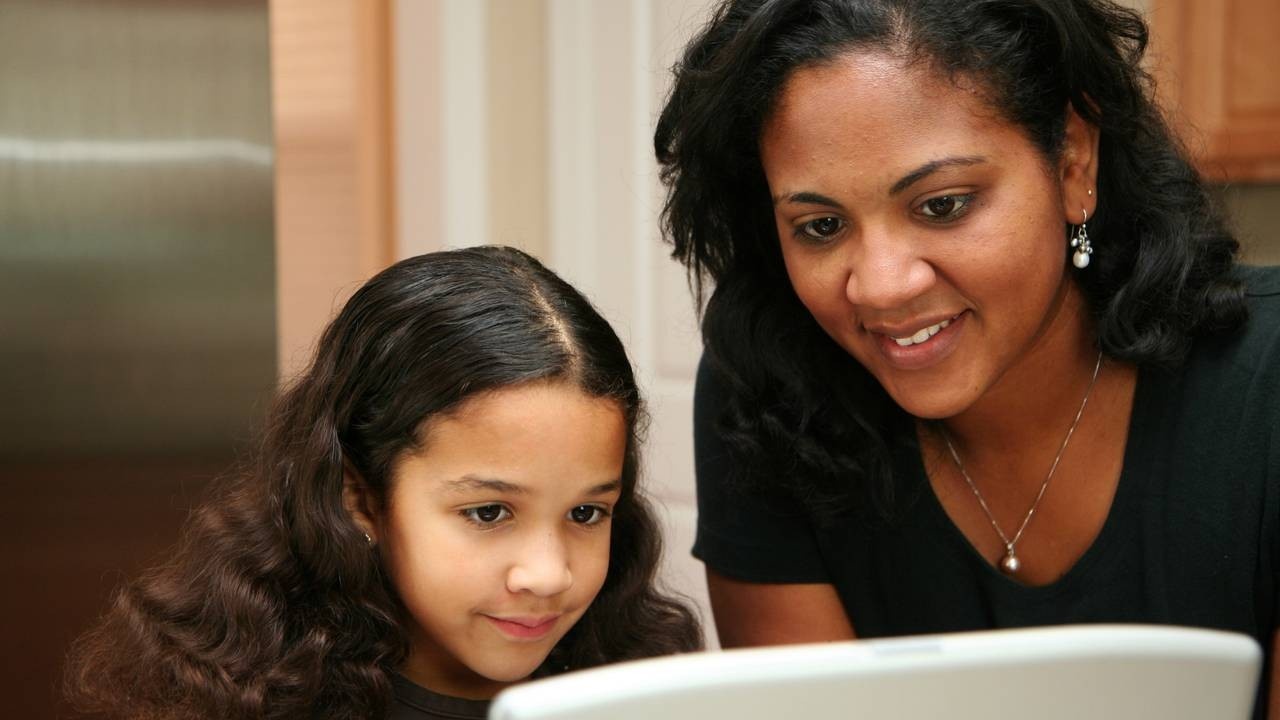 A woman and a child look at a computer screen.