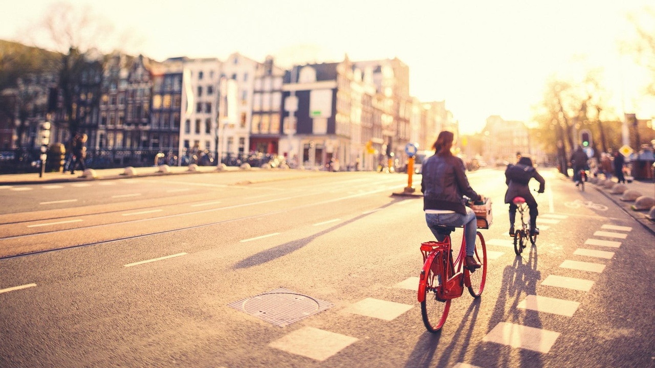 People on bikes in Amsterdam streets at sunset Immigration Attorney ERIN WASLEY Joins Passage Immigration Law