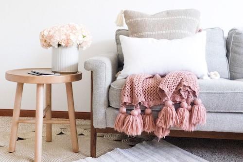 picture of a living room couch with a soft pink throw over it