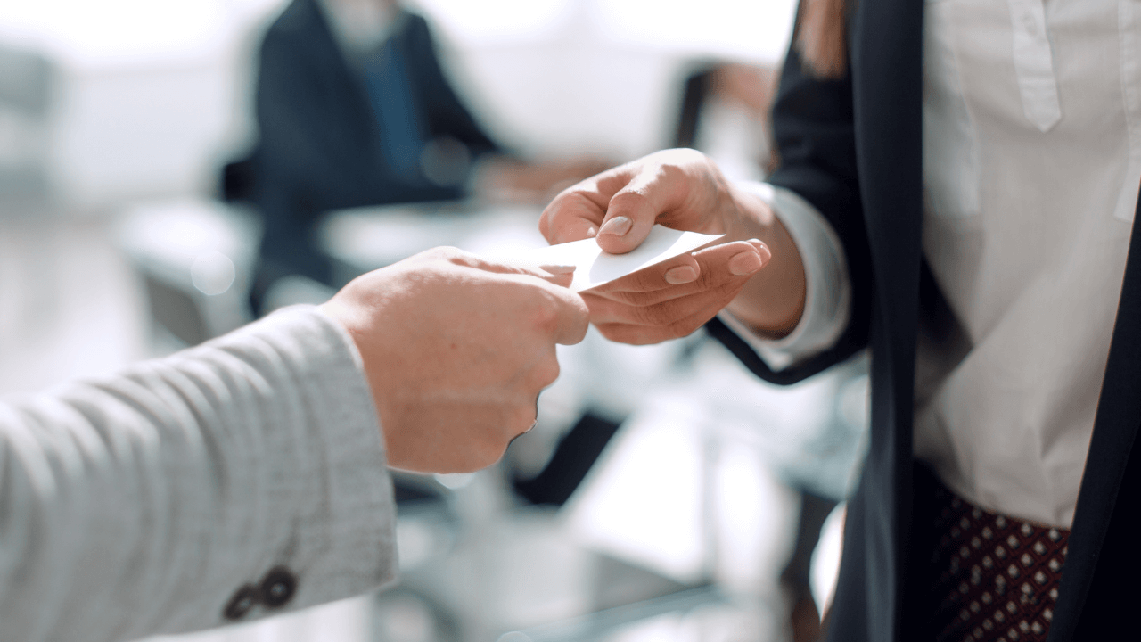 A hand offers a business card to another person's hand