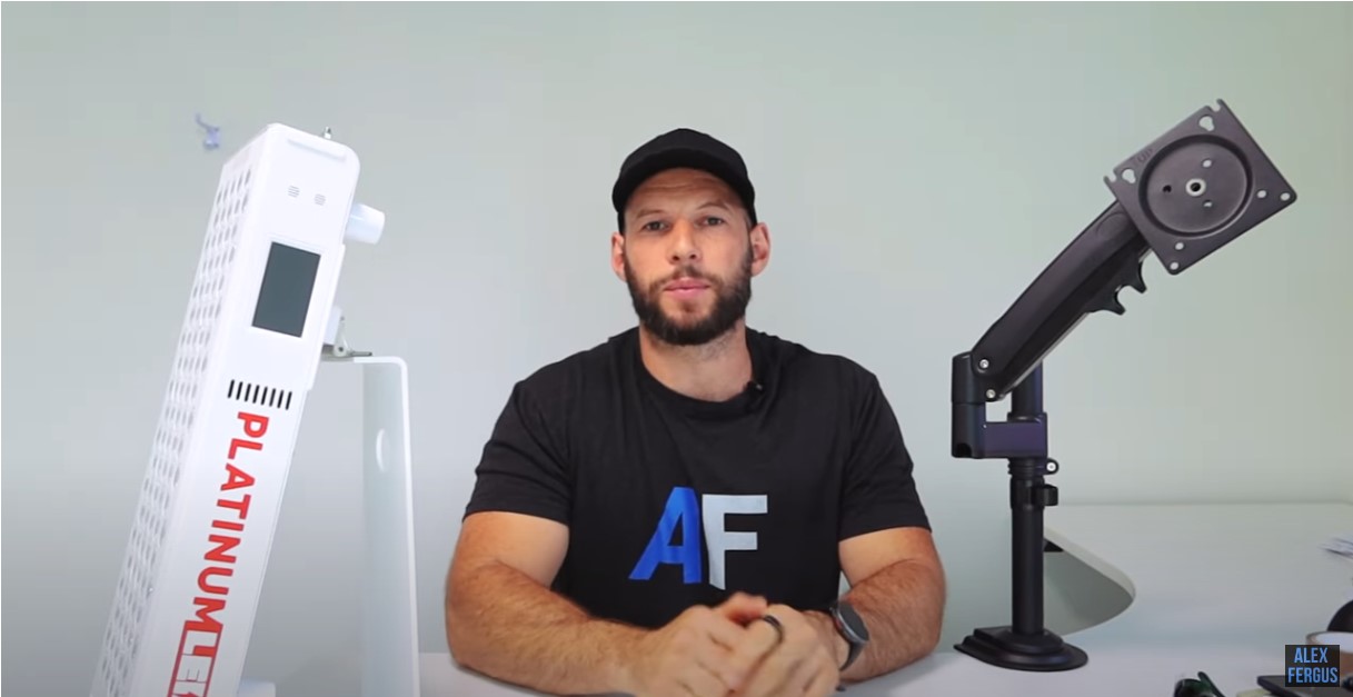 Alex sitting between the PlatinumLED white tabletop stand and the black articulating arm stand 