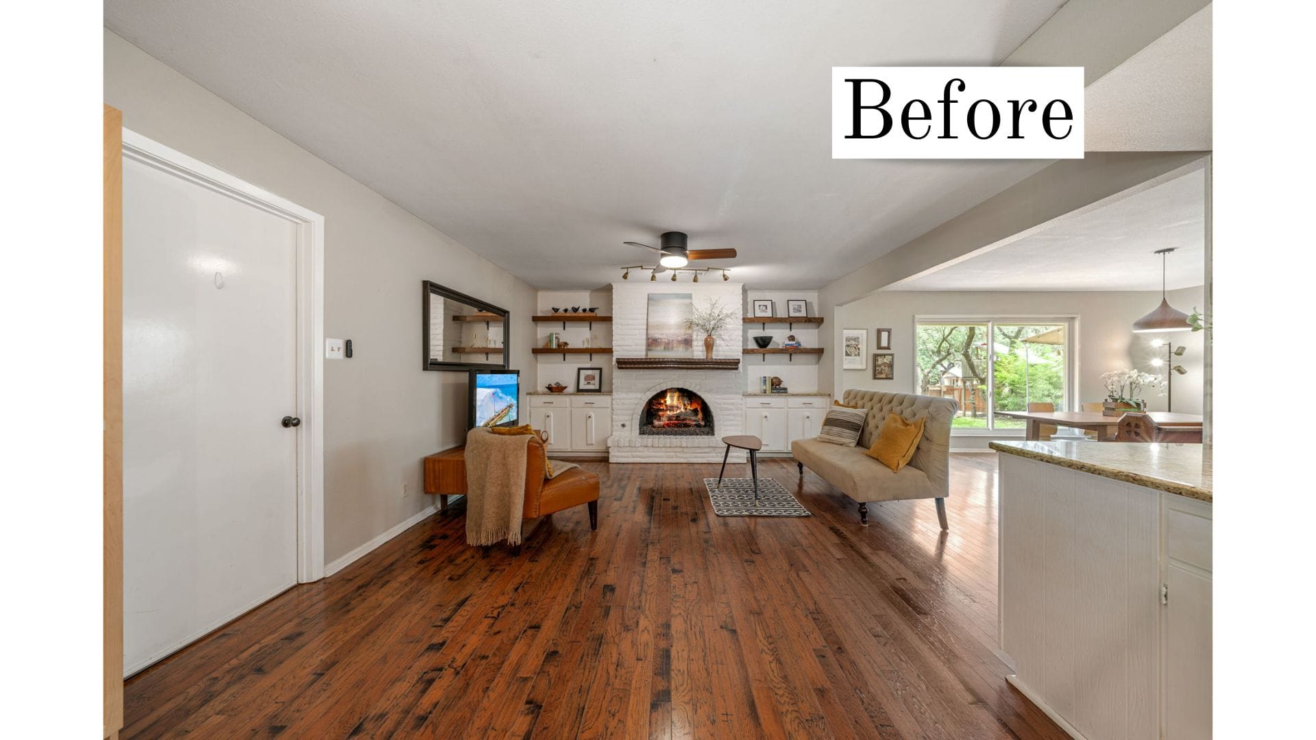 Before home staging living room with fireplace, dark wood floors, minimal furniture, and open-concept layout.