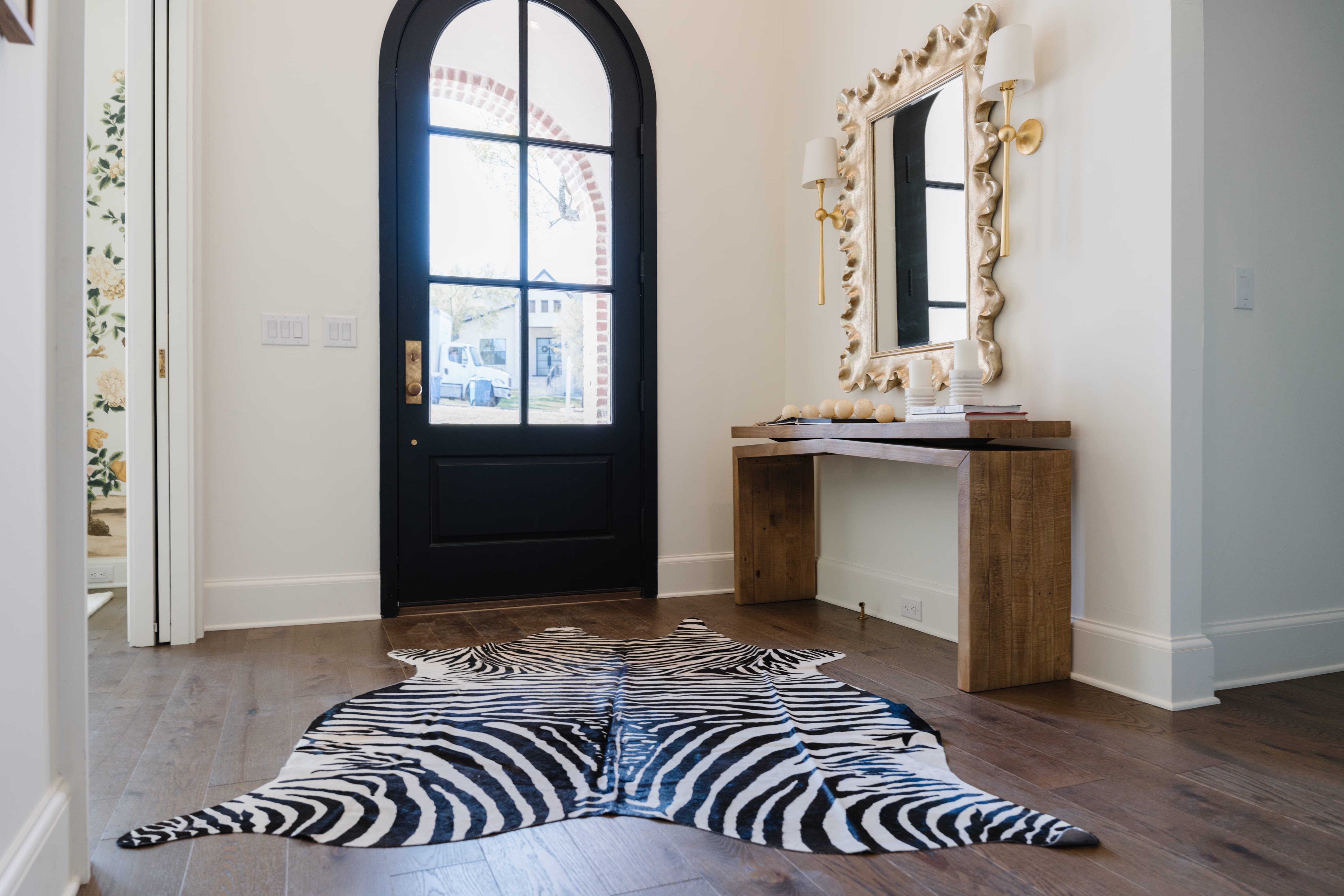Entryway with view into the front room featuring bold floral wallpaper.