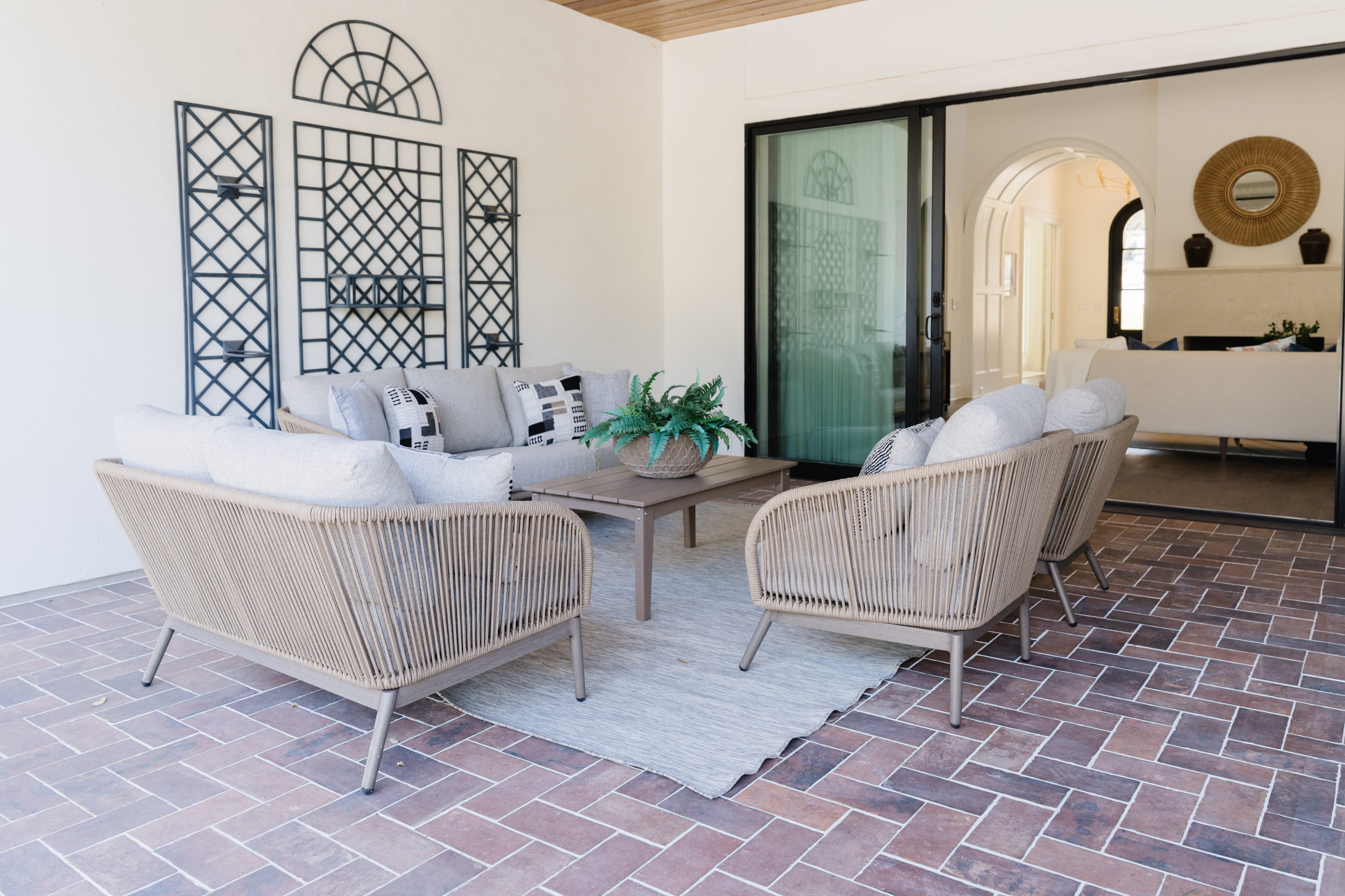 Covered terrace with curved sofa and chairs in natural fibers, French Country style.