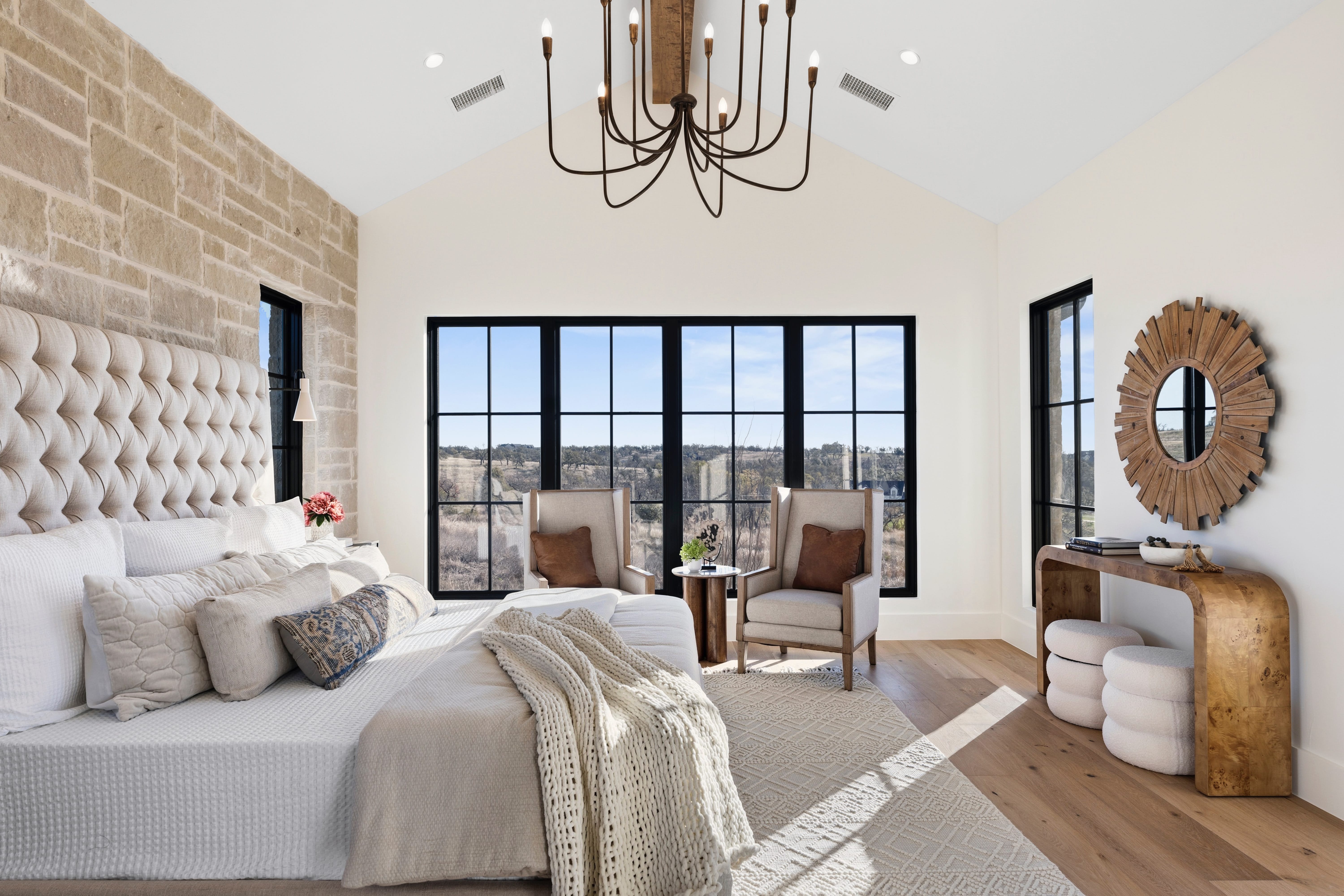 Airy bedroom with a tufted bed and stone accent wall.