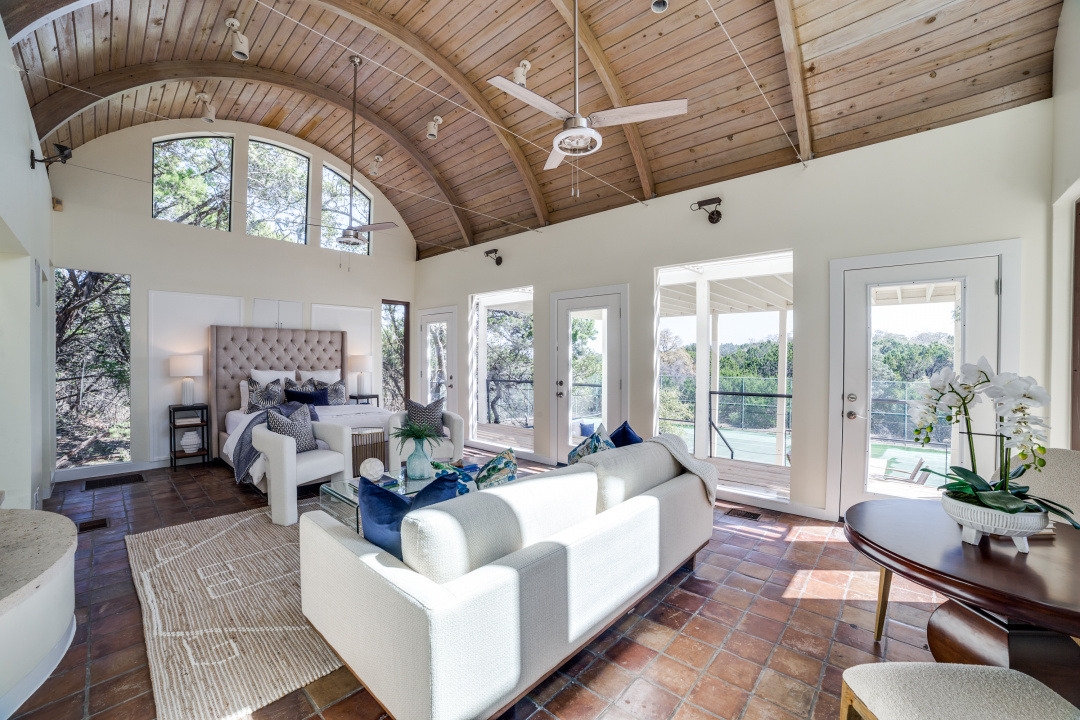 Spacious Boerne estate bedroom featuring high barrel-vaulted ceilings and glass doors.
