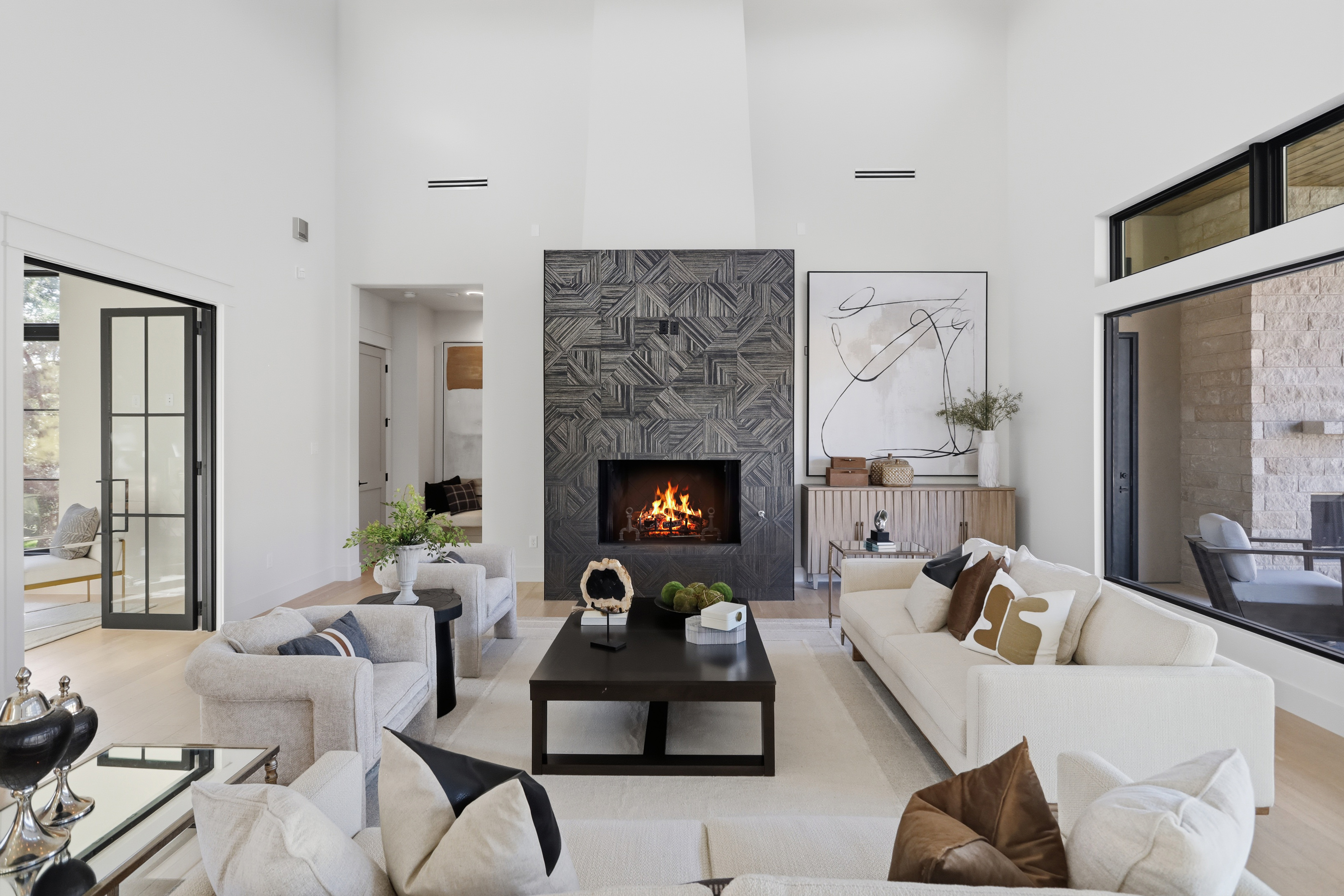 Bright living room with high ceilings, a dark tile fireplace, and cream sofas.
