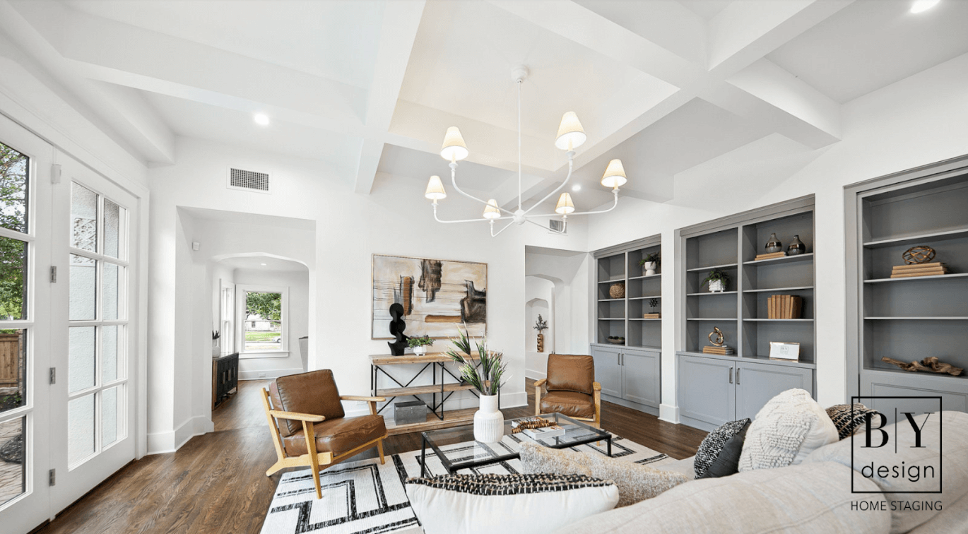 Living room with blue gray open shelving along one wall and brown chairs and earth tone vibes.