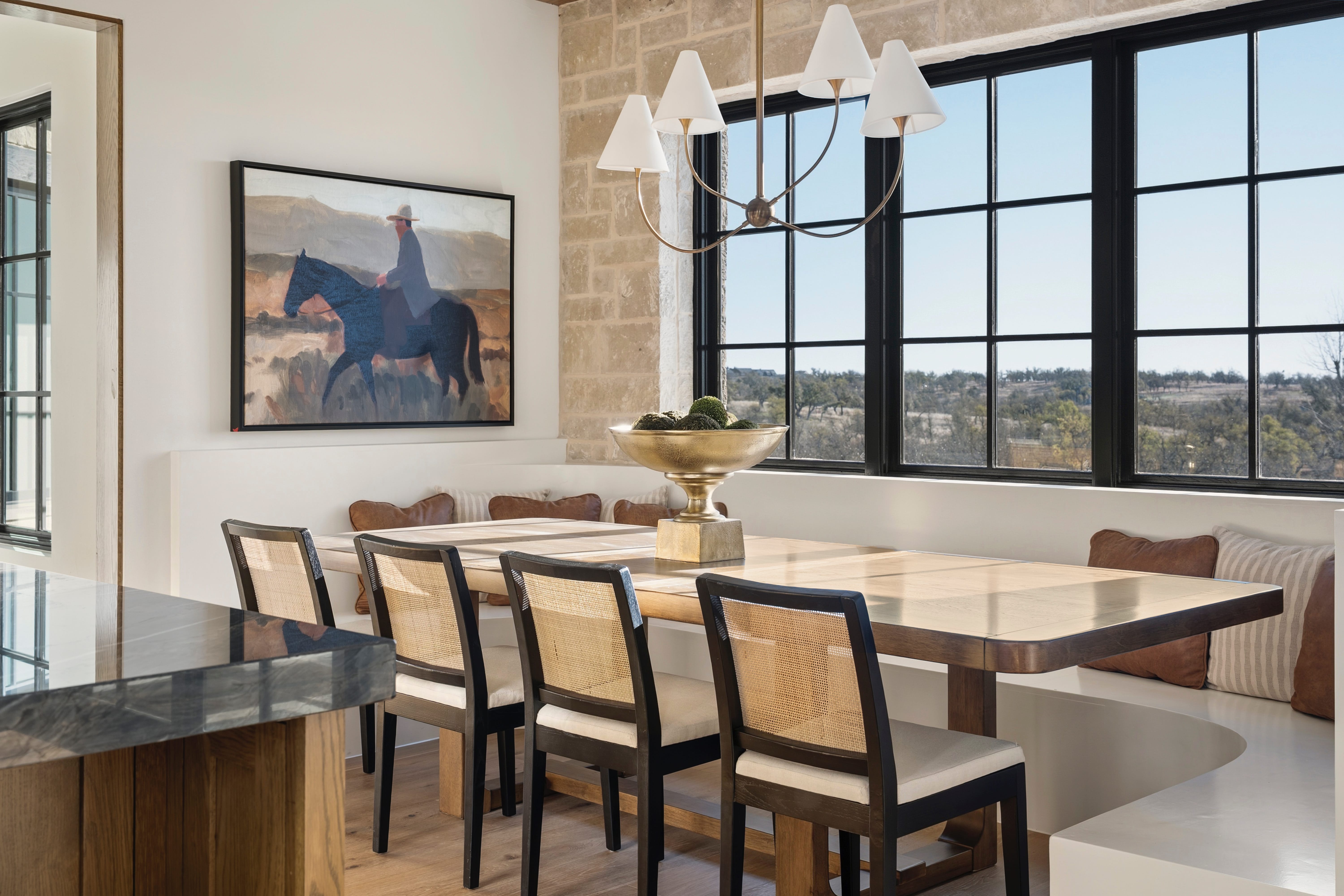 Dining table with cane-back chairs, built-in bench seating, and a painting of a horseback rider.